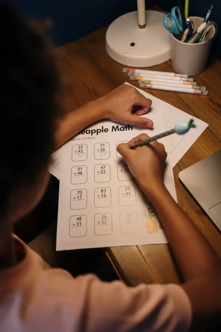 Close-up of a child working through an addition math worksheet with a pencil, building math confidence one problem at a time
