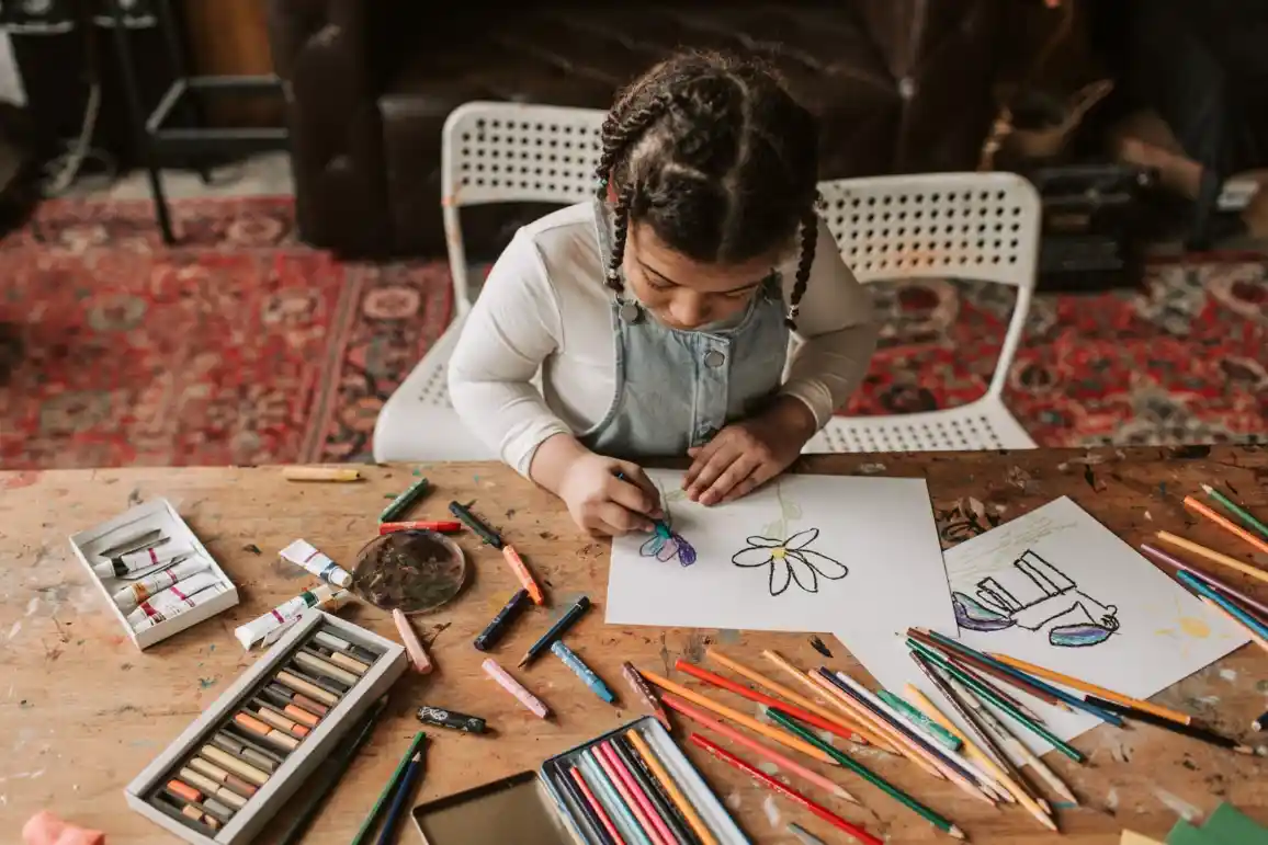 Girl drawing and doing a craft activity at a table
