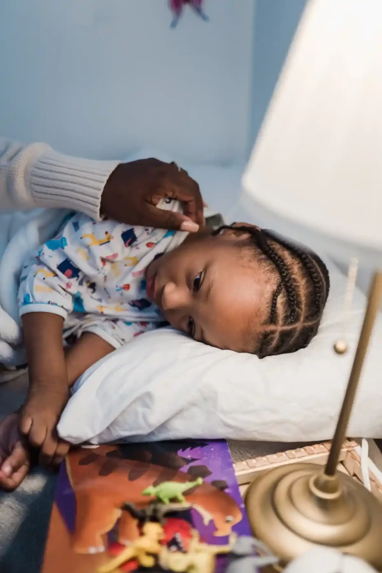 Mother gently tucking her young daughter into bed, creating a calm and loving bedtime routine