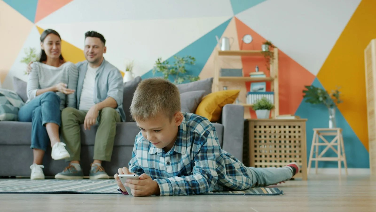 Parents and child looking at a phone together on the couch, illustrating healthy family screen time habits